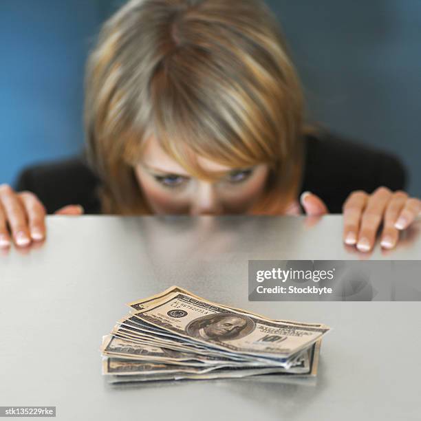 businesswoman watching and tempted by american dollar bills on the table - kärleken till pengar bildbanksfoton och bilder