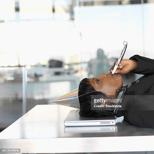 side view of a businesswoman wearing a party hat and blowing a whistle with her head resting on laptop - car horn stock pictures, royalty-free photos & images