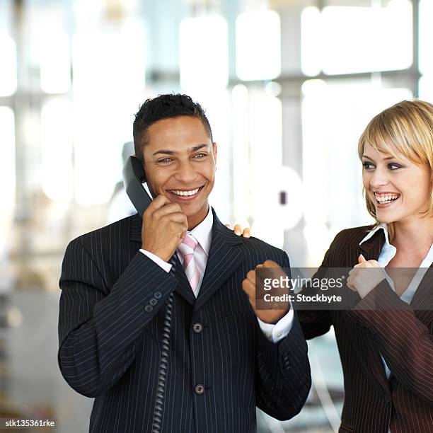 close-up of a businessman talking on the phone with a smile and a colleague cheering him on - man smile stock-fotos und bilder