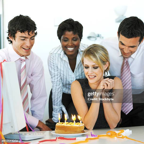 portrait of a woman sitting across her birthday cake with co-workers standing behind her - across stock pictures, royalty-free photos & images