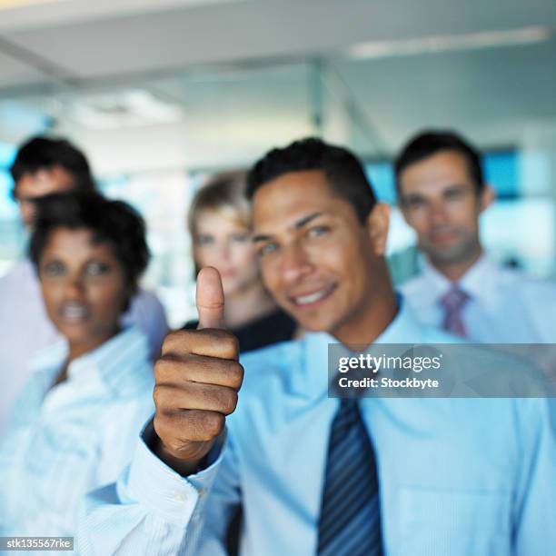 a young business man giving the ok hand signal with a group of business executives standing behind - signal stock-fotos und bilder