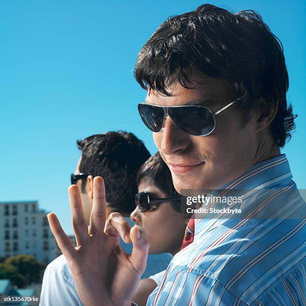 businessman wearing sunglasses giving the ok hand signal - signal stock-fotos und bilder