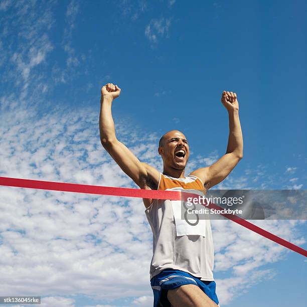 low angle view of man running, reaching finish line - crossed stock pictures, royalty-free photos & images