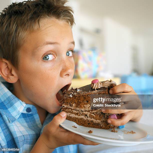 close-up of a young boy (8-10) eating a slice of chocolate cake - slice stock pictures, royalty-free photos & images