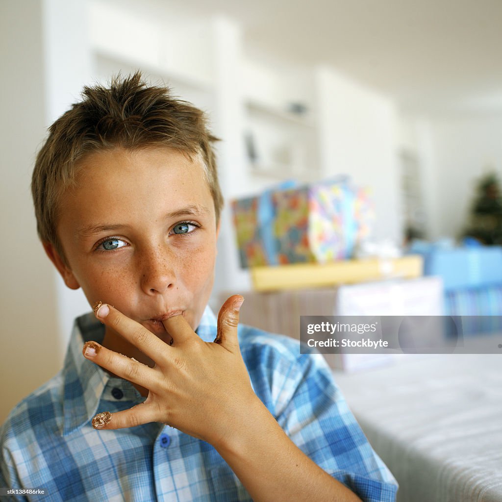Portrait of a young boy licking his finger