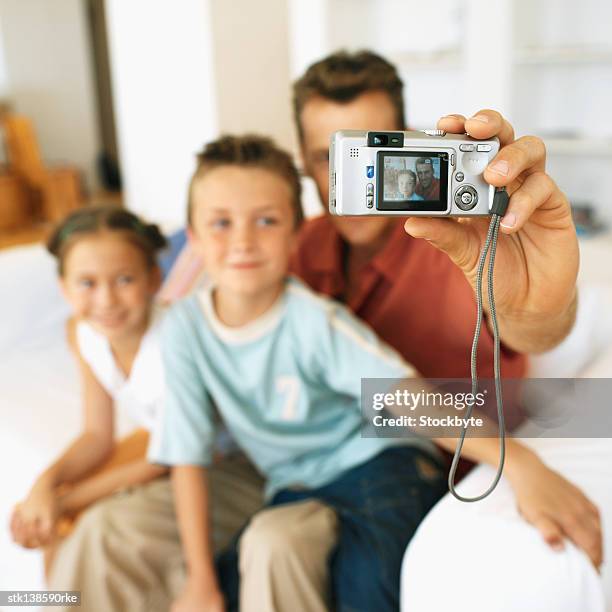 father holding camera taking a picture of himself son (8-9) and daughter (12-13) - camera picture ストックフォトと画像