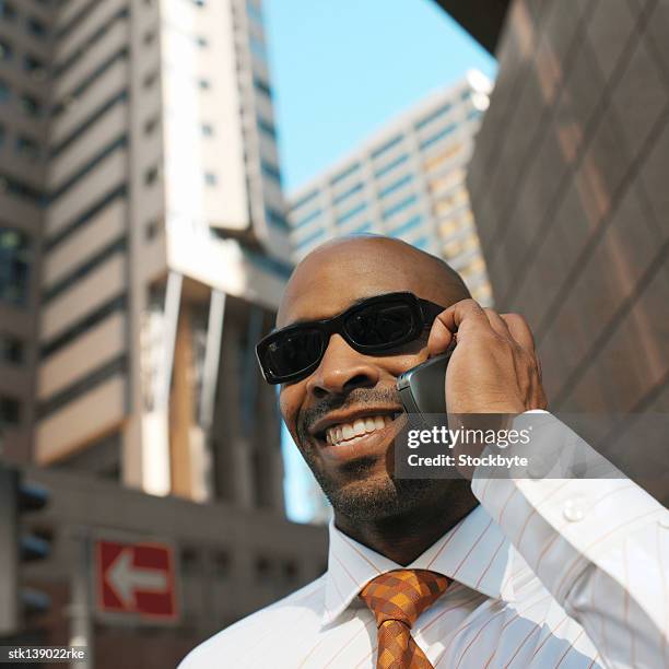 close-up of a young businessman smiling talking on a mobile phone - best sunglasses for bald men fotografías e imágenes de stock