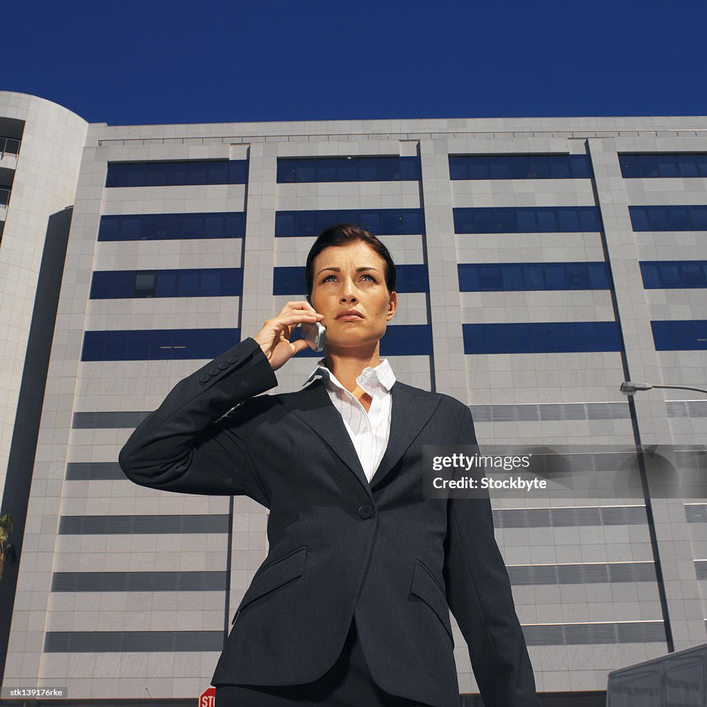 Businesswoman talking on a mobile phone standing in front of an office building