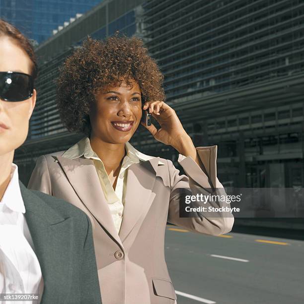 close up of two businesswomen one of which is talking on mobile phone - is stock pictures, royalty-free photos & images