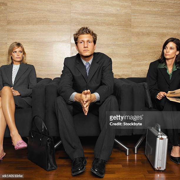 businessman sitting between two businesswomen in an office lobby - between bildbanksfoton och bilder