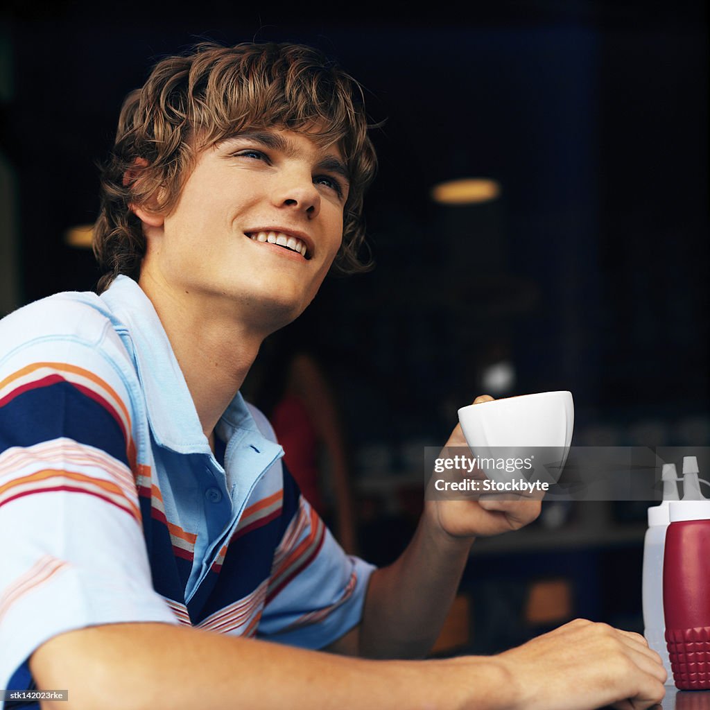 Close up of a young man drinking cup of coffee