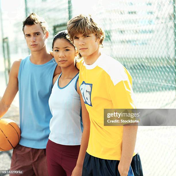 close-up of a teenage girl standing between two boys with a basketball, side profile - woman yellow basketball stock pictures, royalty-free photos & images