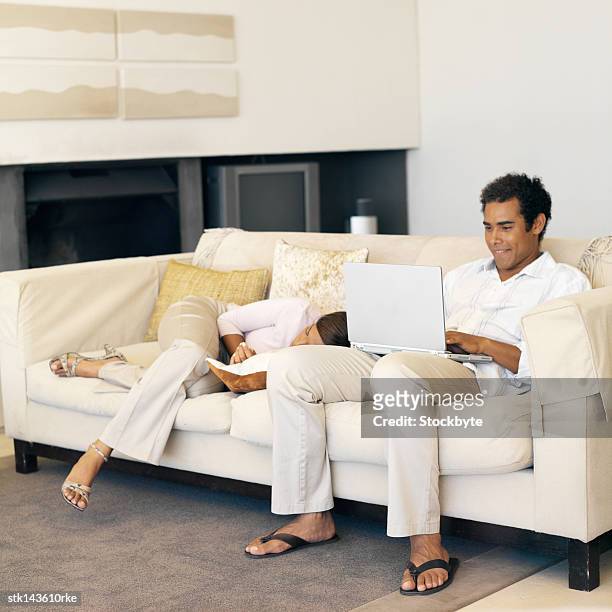 young man working on laptop while young woman sleeps next to him - next stockfoto's en -beelden