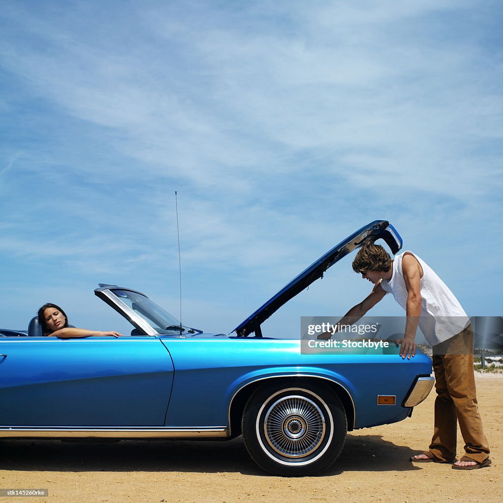 Young couple driving in convertible car hood raised