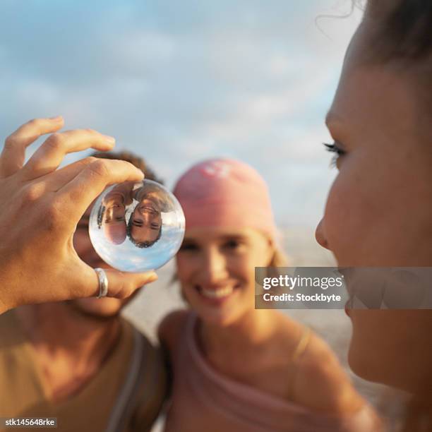 young woman looking at friends reflection through crystal ball - reflection foto e immagini stock