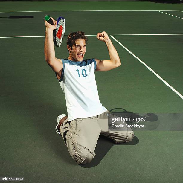 elevated view of a man on his knees in a tennis court celebrating his victory - tennis court stock pictures, royalty-free photos & images