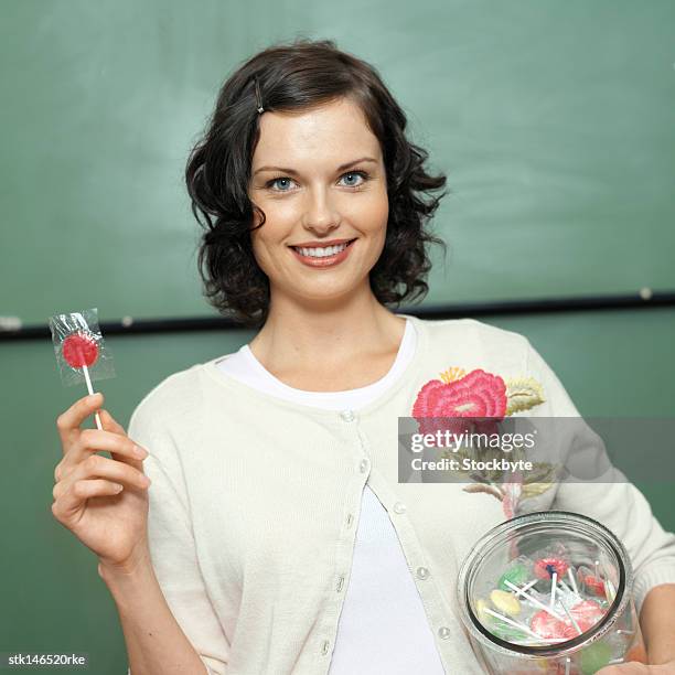 portrait of a young female teacher holding a jar of candy - candy jar stock pictures, royalty-free photos & images