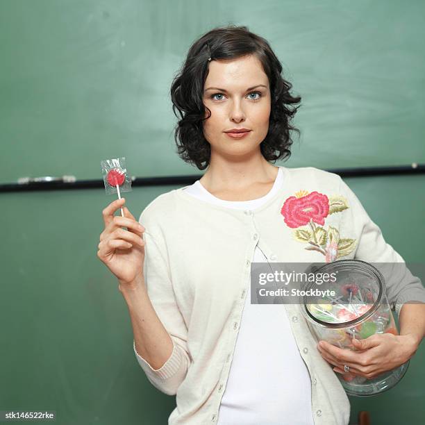portrait of a young female teacher holding a jar of candy - candy jar stock pictures, royalty-free photos & images