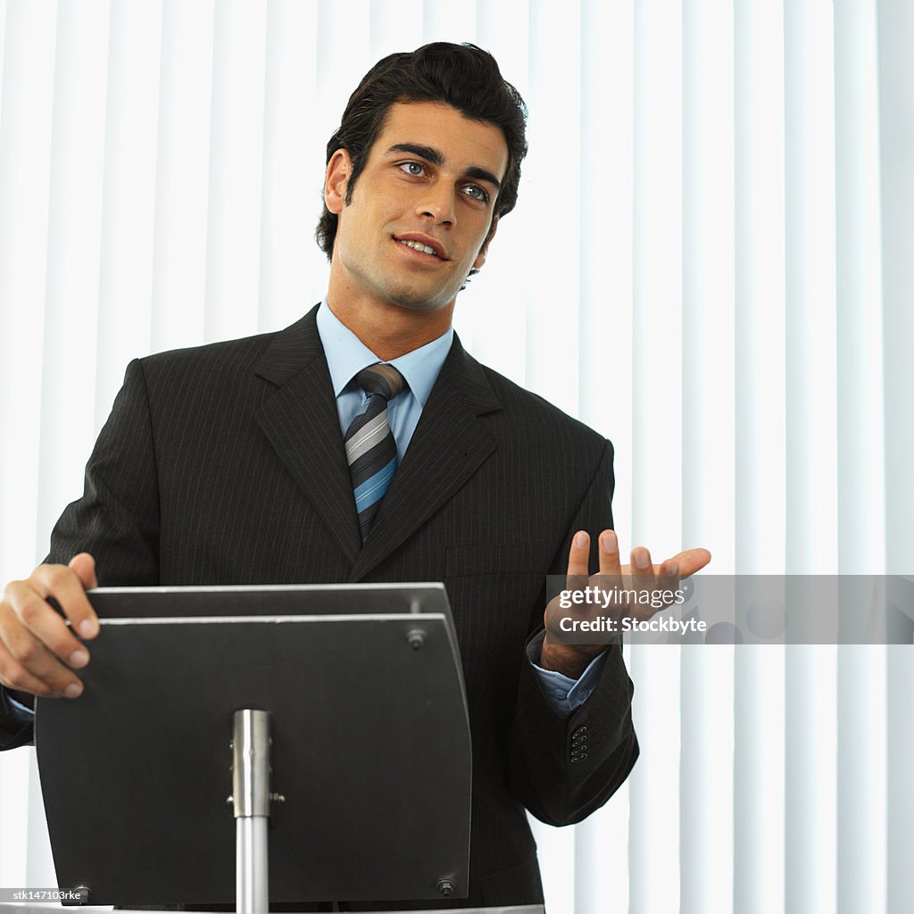 Portrait of a businessman standing behind a podium giving a speech