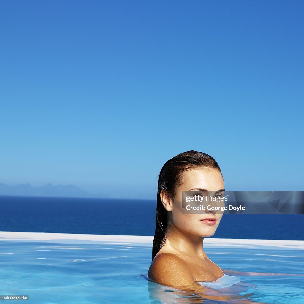 Young woman standing in swimming pool side view