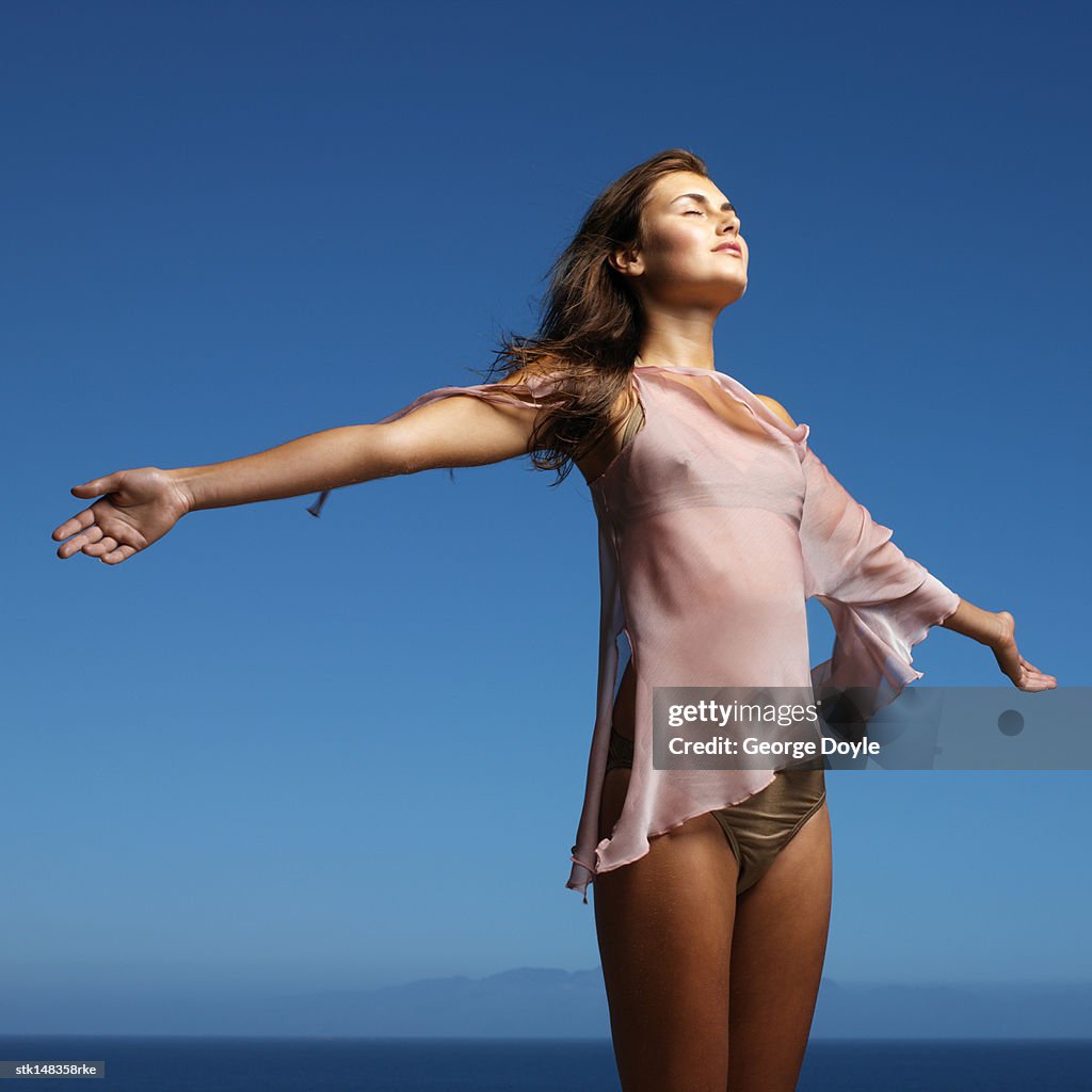 Young woman standing holding hands out low angle view