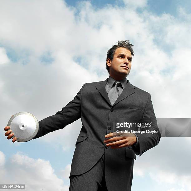 low angle view of a businessman throwing a disc - men's field event stockfoto's en -beelden