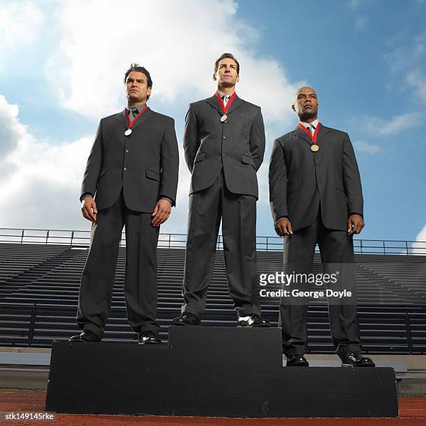 low angle view of businessmen standing in a stadium wearing  medals - winners podium people stock pictures, royalty-free photos & images