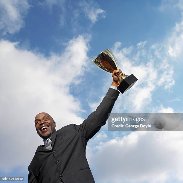 low angle view of a businessman holding a trophy cup - low motivation stock pictures, royalty-free photos & images