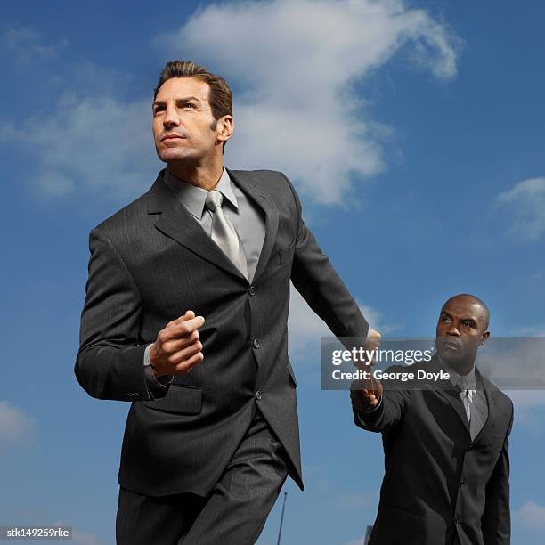 low angle view of two businessmen exchanging baton in a relay race - sports competition format stock pictures, royalty-free photos & images