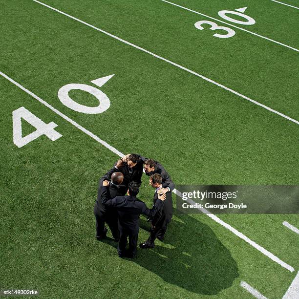 high angle view of businessmen in a huddle on a football field - george nader stockfoto's en -beelden