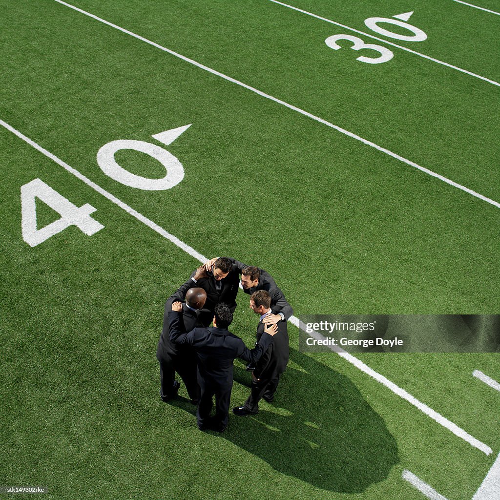 High angle view of businessmen in a huddle on a football field
