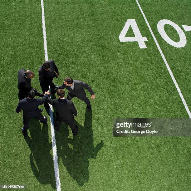 high angle view of  businessmen in a huddle on a football field - george nader stockfoto's en -beelden