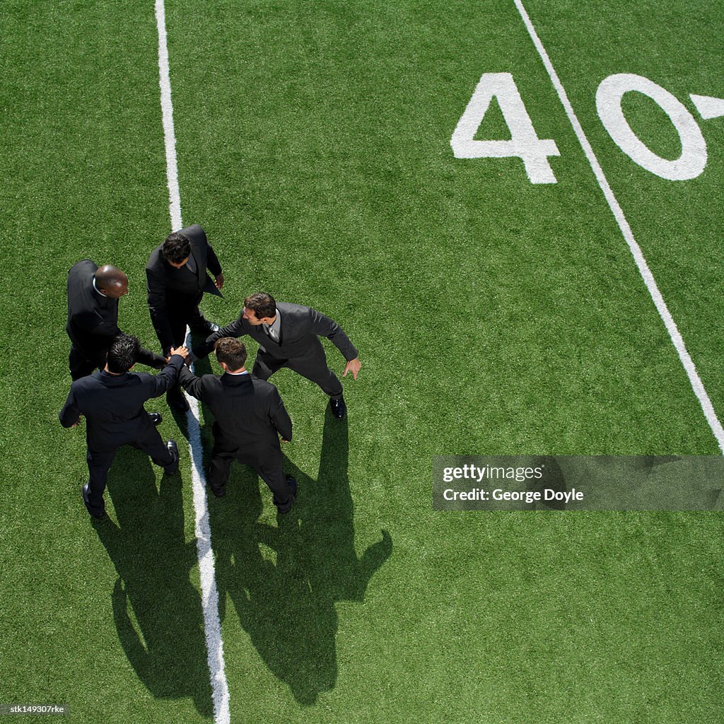 High angle view of businessmen in a huddle on a football field