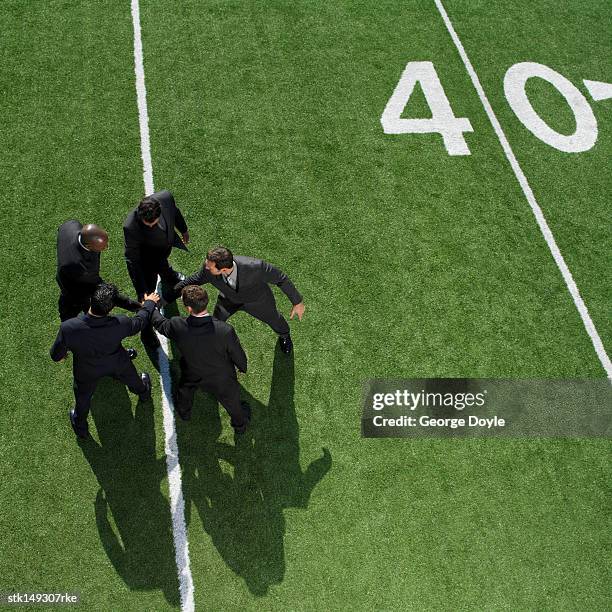 high angle view of  businessmen in a huddle on a football field - forty yard line stock pictures, royalty-free photos & images