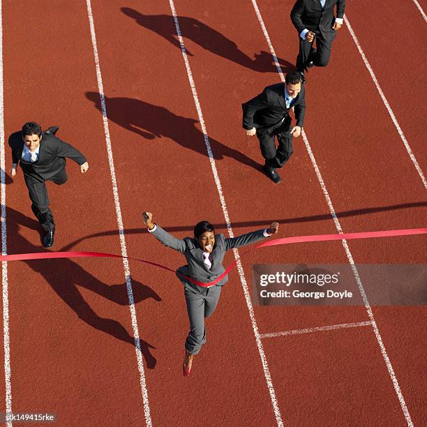 high angle view of a businesswoman crossing the finish line ahead of businessmen - ahead stock pictures, royalty-free photos & images