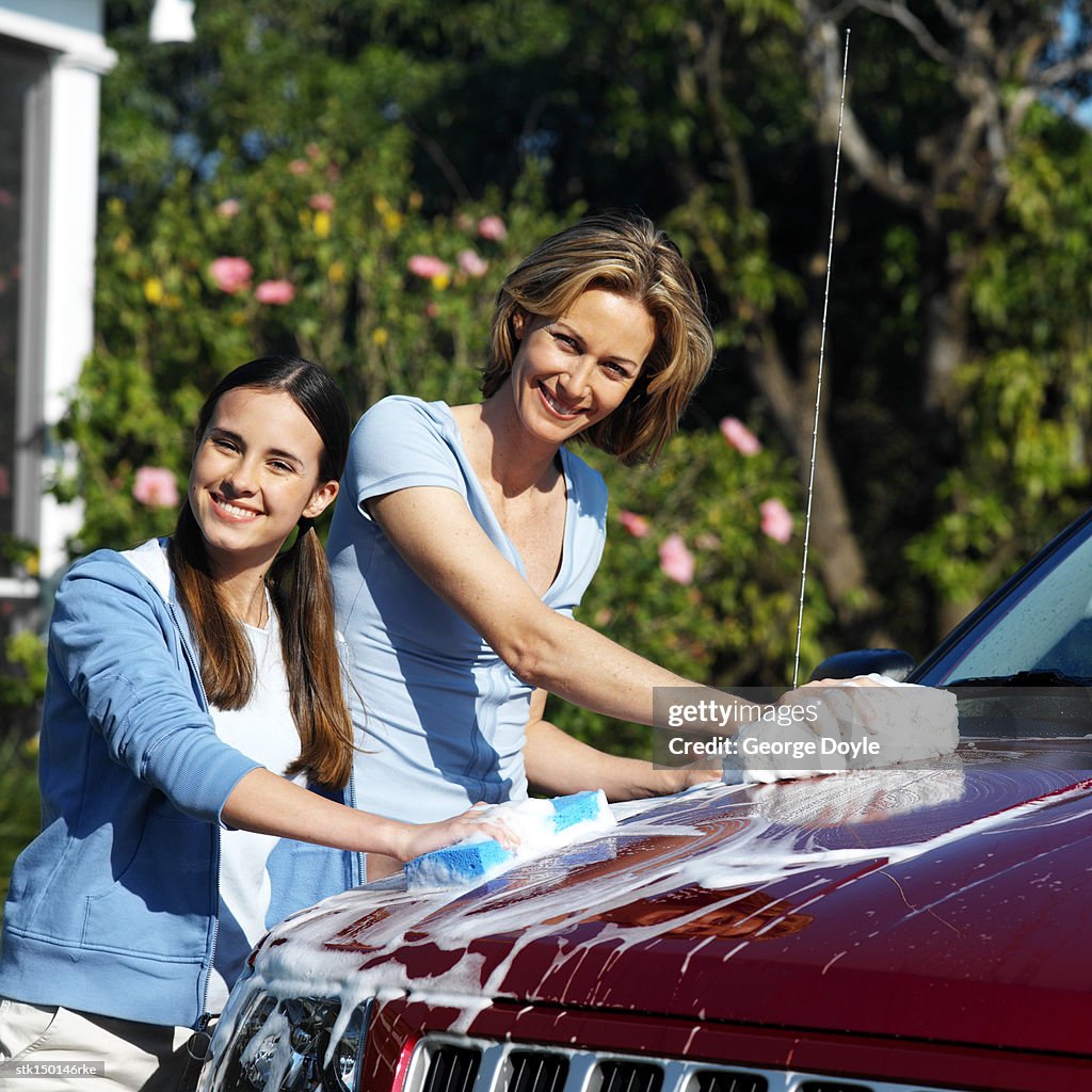 Portrait of a mother and teenage daughter (17-18) washing the car
