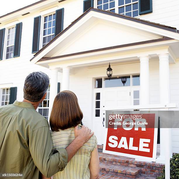 back of a couple looking at a house for sale - for sale stockfoto's en -beelden