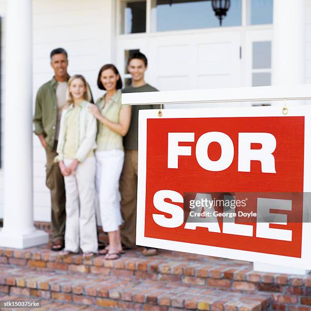 portrait of a father with son and daughter standing behind a 'for sale' sign - for sale stockfoto's en -beelden