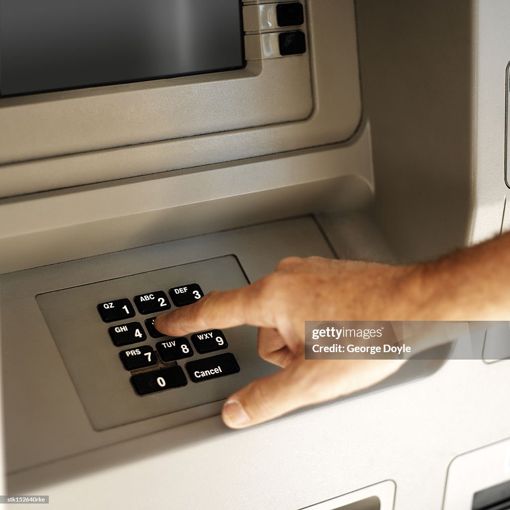 Close-up of a human hand entering a code number at an automatic cash machine