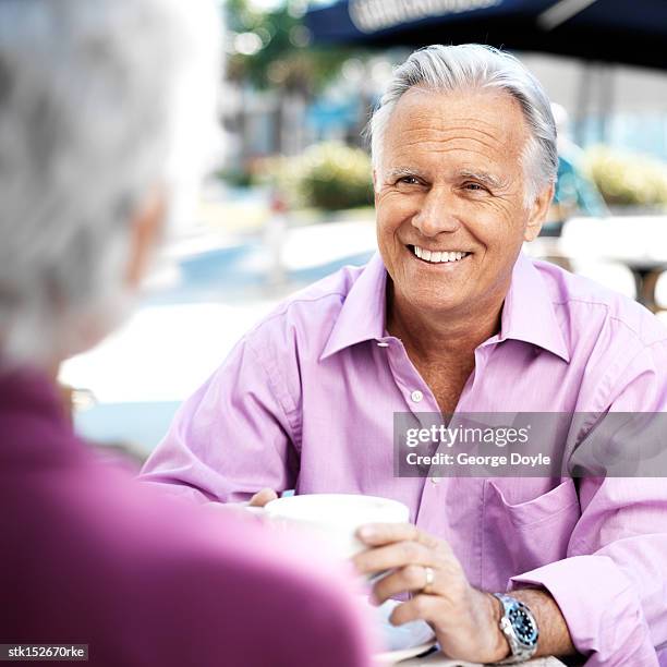 a mature couple talking over coffee at an outdoor caf? - purple shirt stock-fotos und bilder