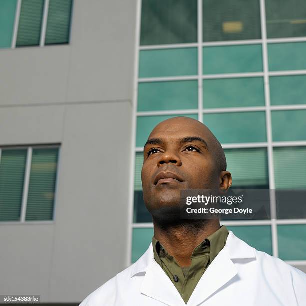 young male microbiologist standing outdoors looking ahead - get ahead stock-fotos und bilder