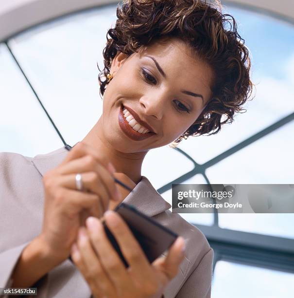 low angle view of a young woman using a hand held device - george nader stockfoto's en -beelden