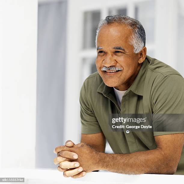 elderly man leaning against a railing looking ahead - get ahead stock-fotos und bilder