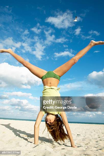 a young woman doing the handstand at the beach - duing stock pictures, royalty-free photos & images