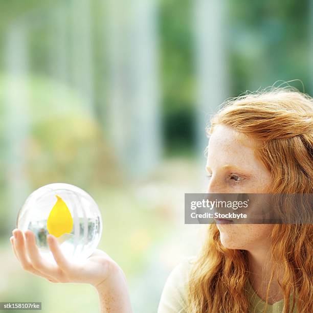 portrait of a young girl (14-16) looking at a crystal ball  with a flower inside - crystal stock-fotos und bilder