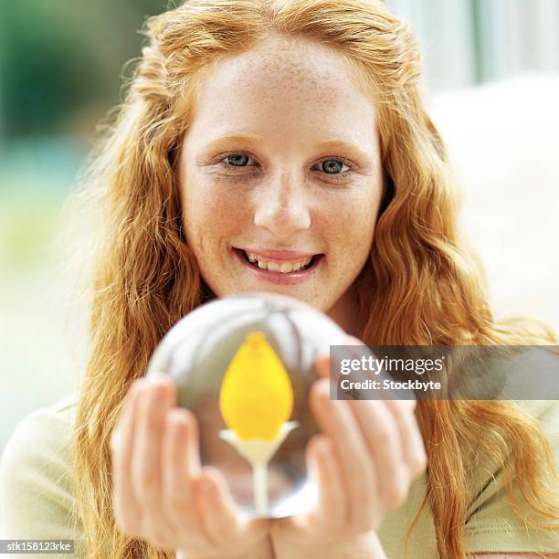 portrait of a young girl smiling and holding a crystal ball - crystal stock-fotos und bilder