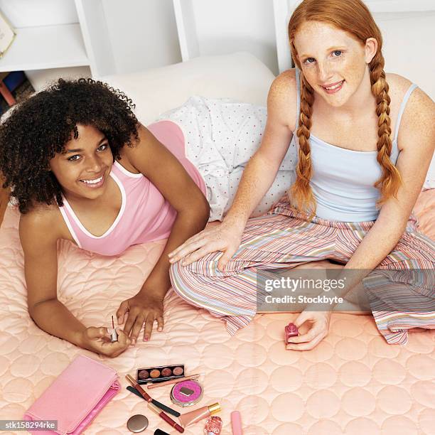 elevated view two teenage girlfriends (16-18) at a sleepover painting nails - night in fotografías e imágenes de stock