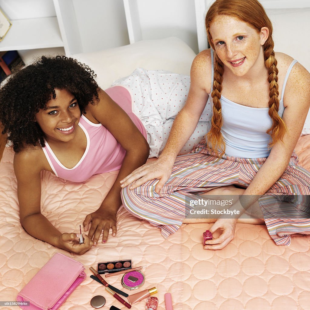 Elevated view two teenage girlfriends (16-18) at a sleepover painting nails