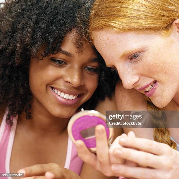 two young girls sitting closely looking in compact case - night in fotografías e imágenes de stock