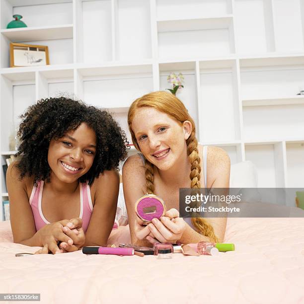 portrait of two young girls lying on bed smiling - night in fotografías e imágenes de stock